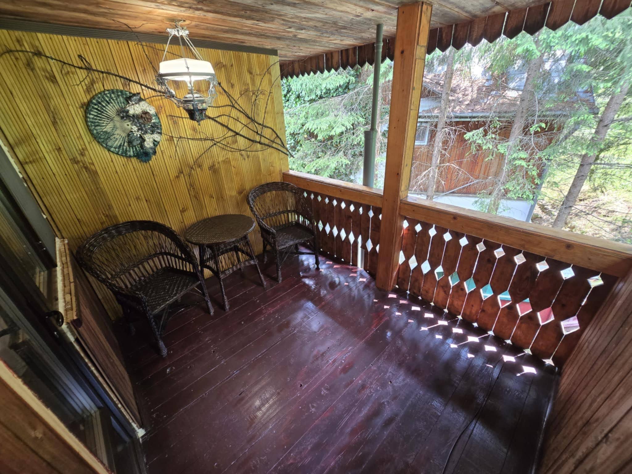 Covered wooden balcony overlooking dense green forest.