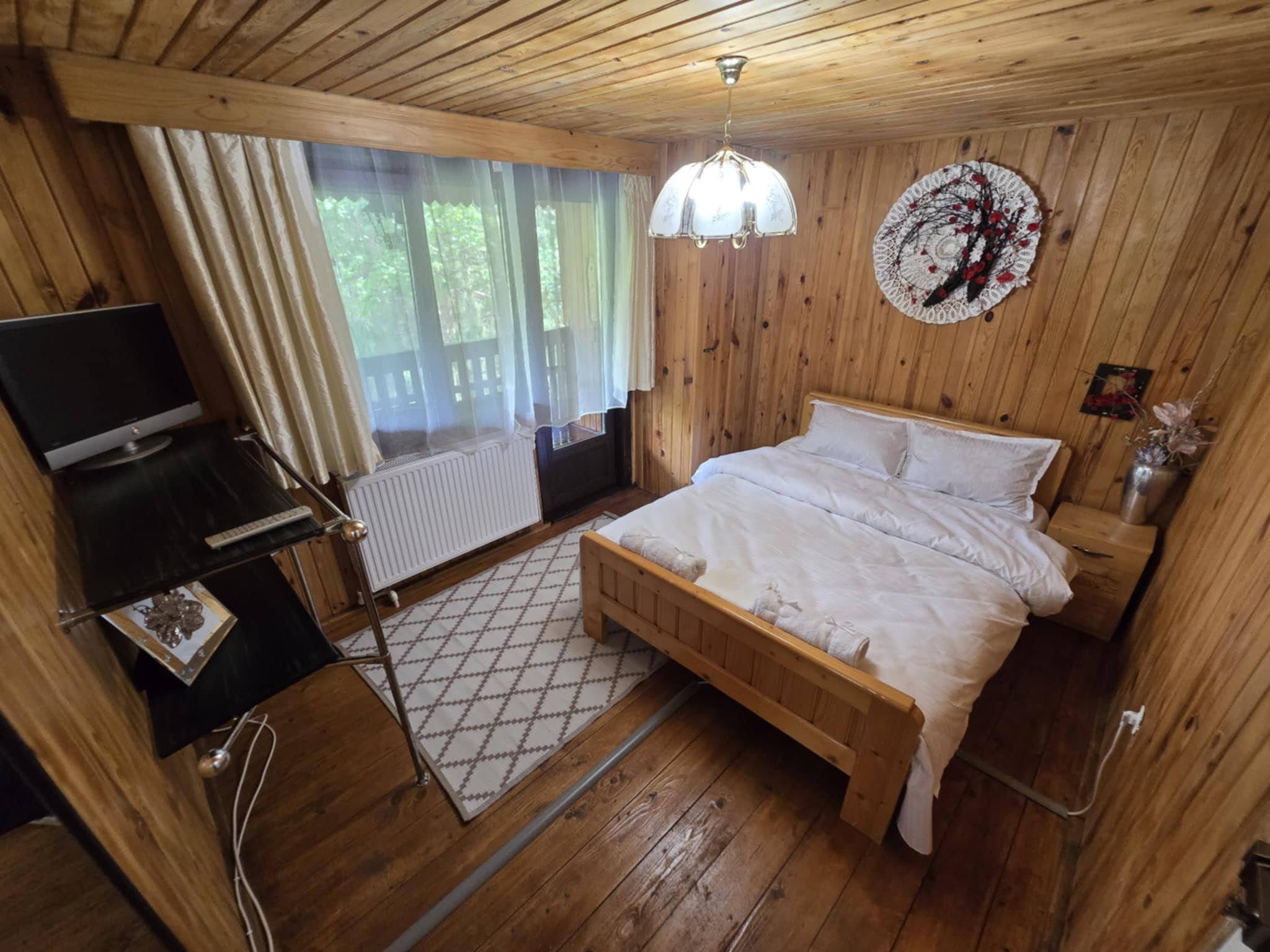 Warm wood-panelled double bedroom with windows onto the garden.