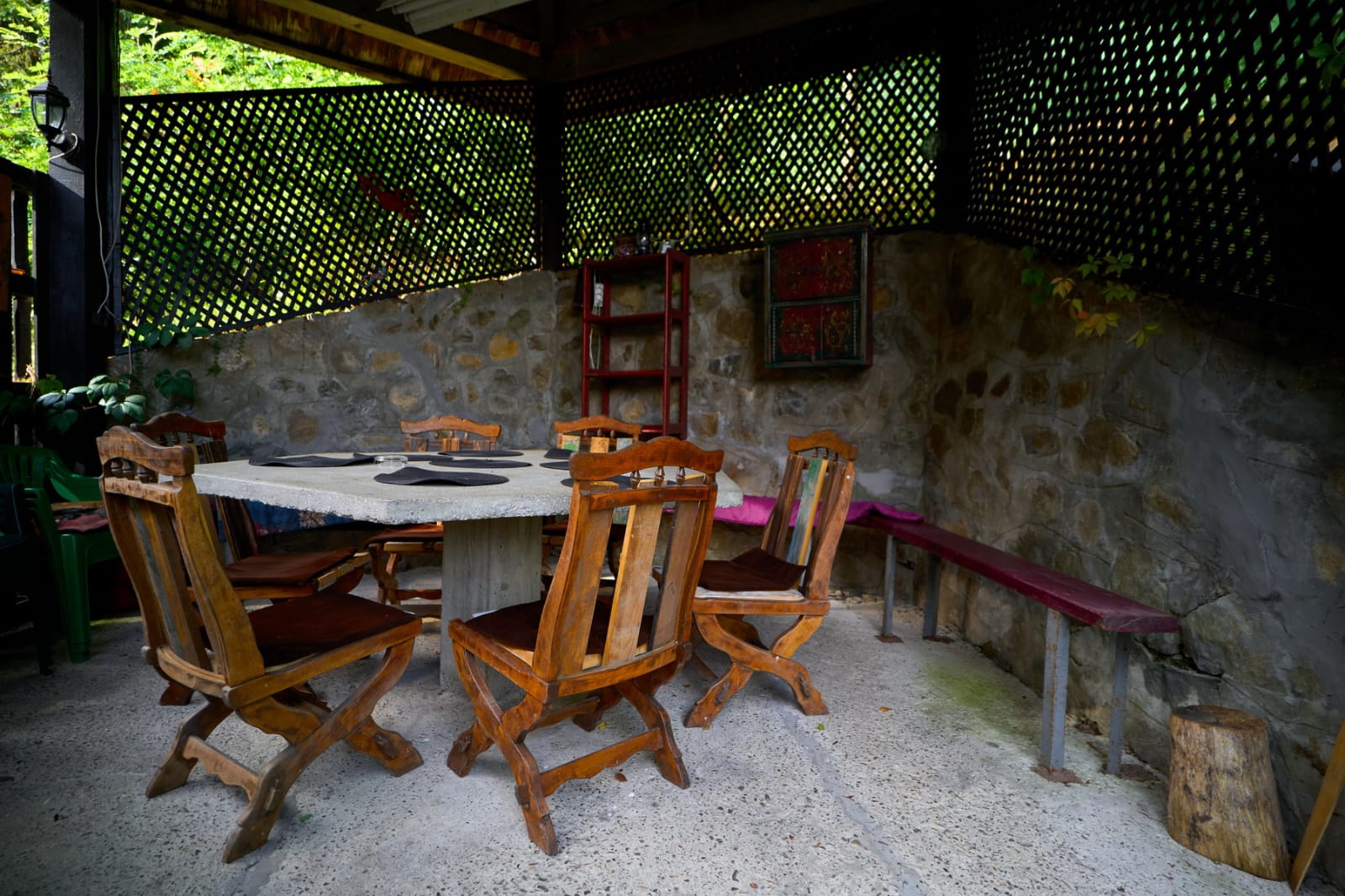 Covered outdoor dining area with handmade wooden chairs and stone walls.