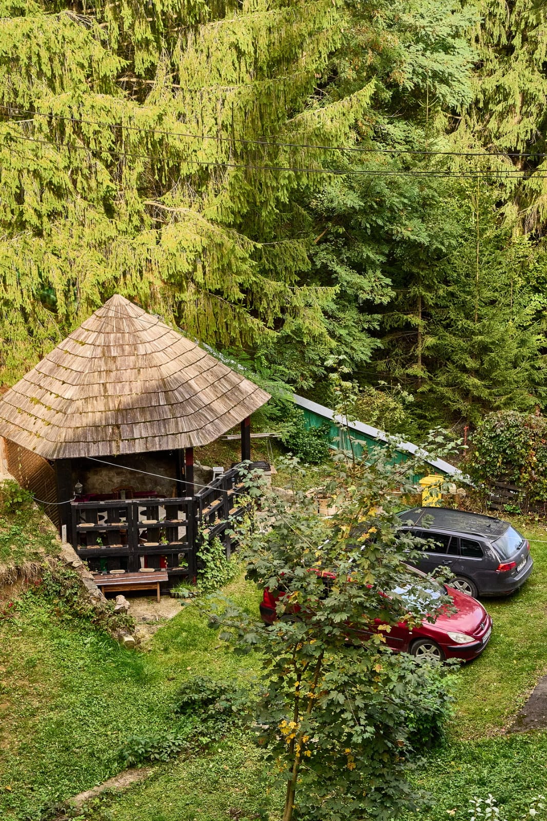 Timber garden gazebo and parking area surrounded by forest.