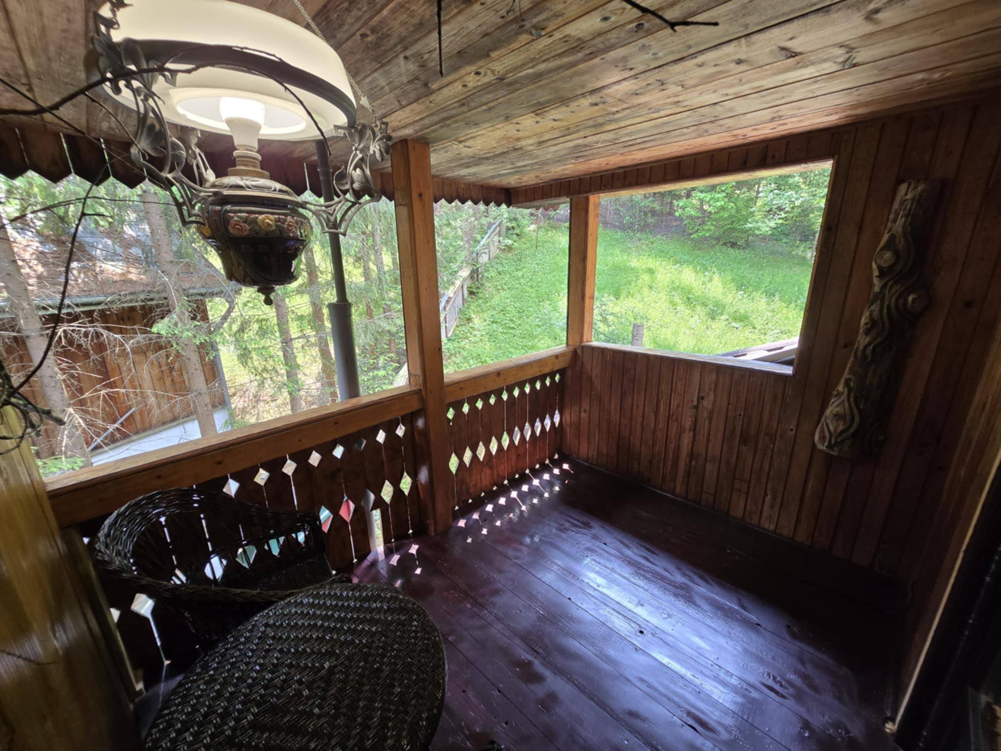 Sheltered porch corner with chairs and forest views.