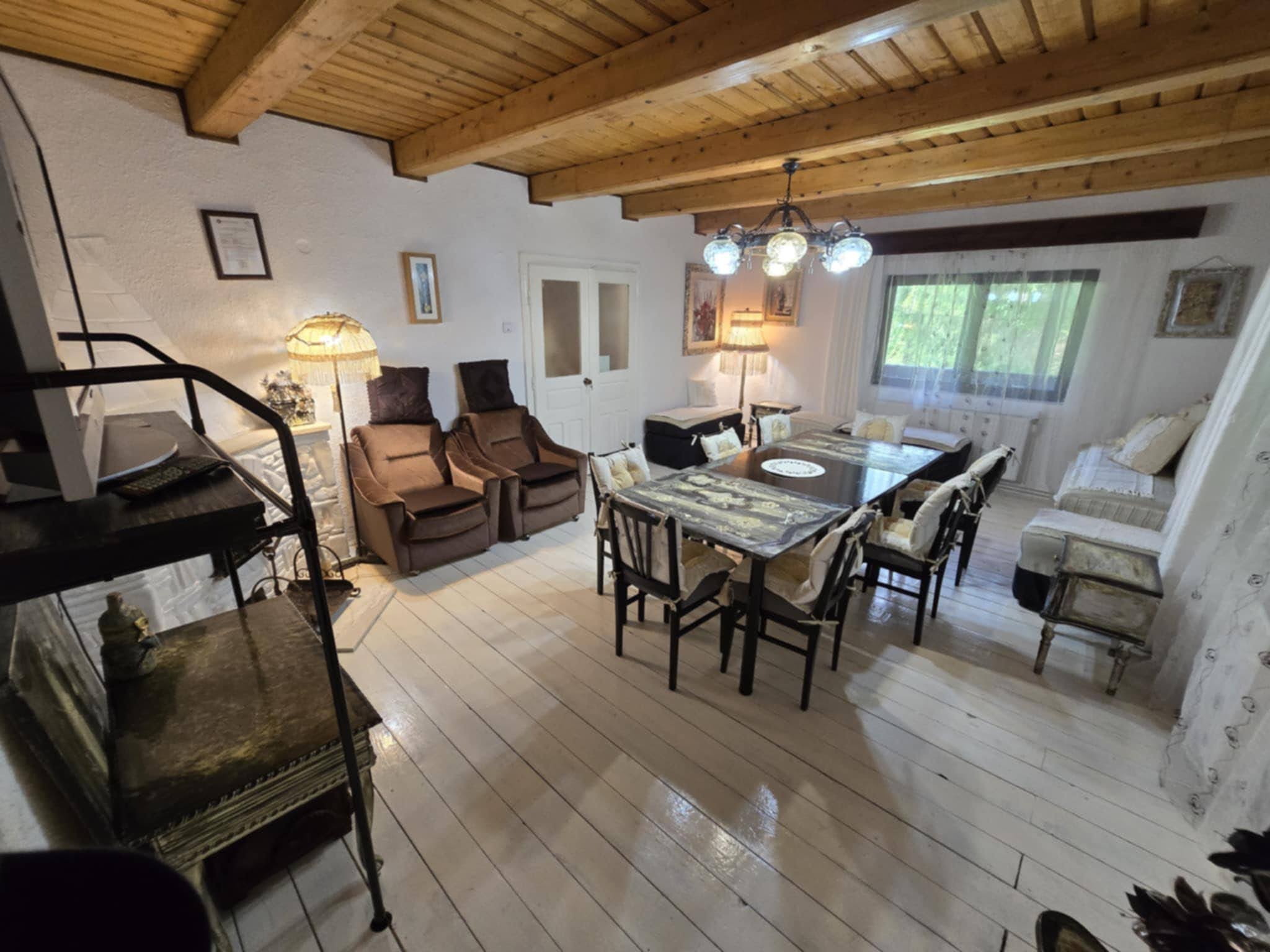 Shared living room with exposed beams, dining table and kitchenette.