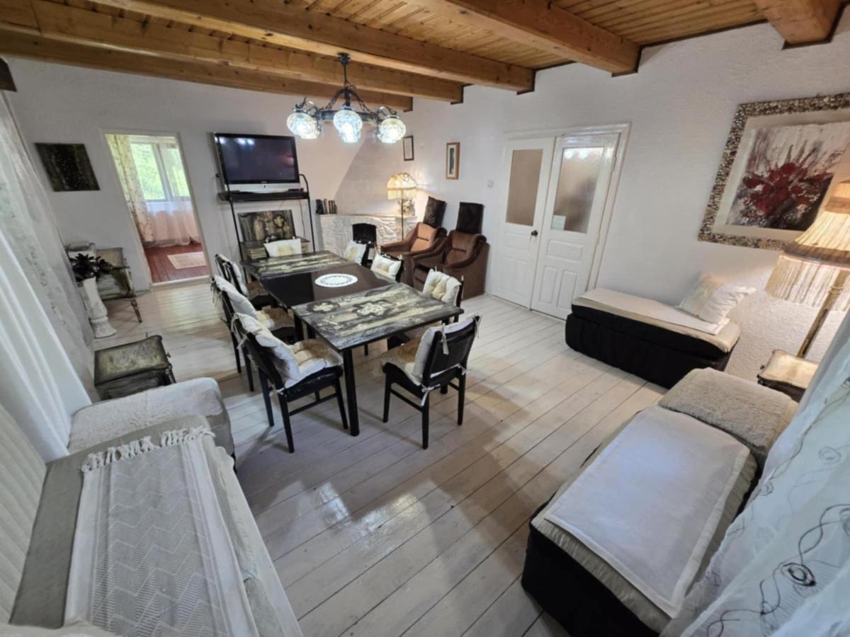 The living room at Casa Daniela, with exposed timber beams, a wrought-iron chandelier, wide whitewashed floorboards, a long dining table and a hearth.